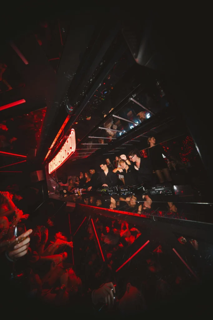 DJ en train de mixer devant une foule à La Dame Bordeaux avec ambiance rouge et lumières en club