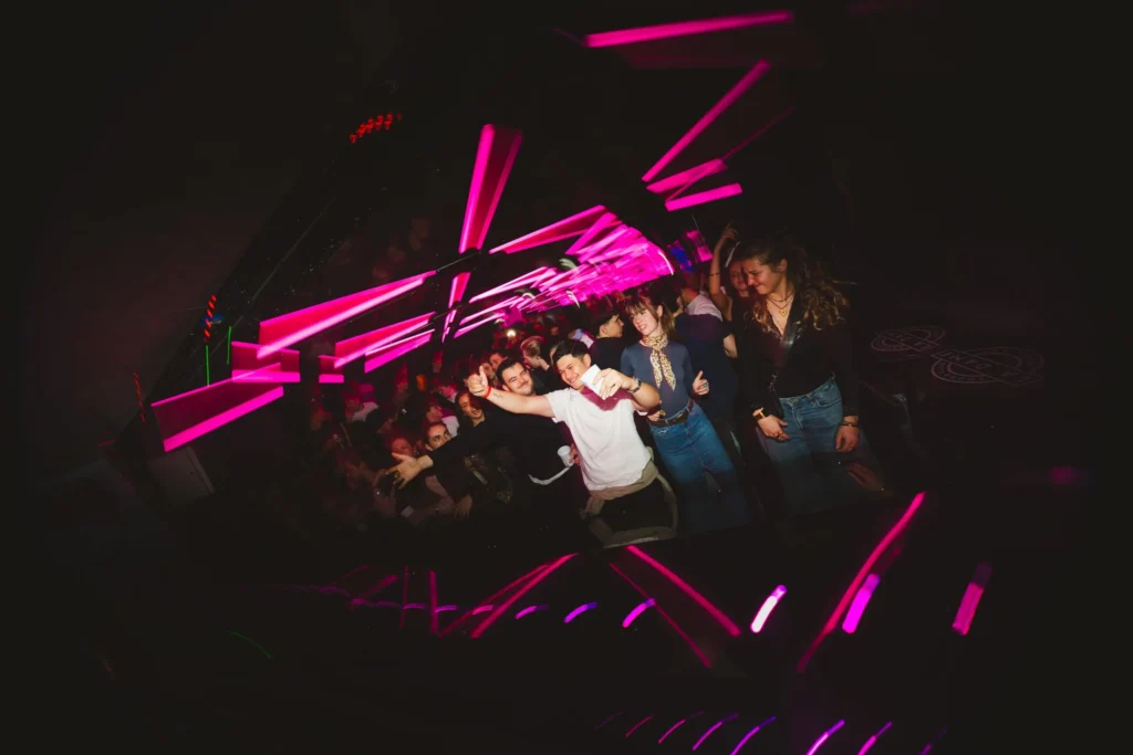 Groupe de personnes en soirée à La Dame Bordeaux avec lumières néon roses dans un club aux Bassins à Flots