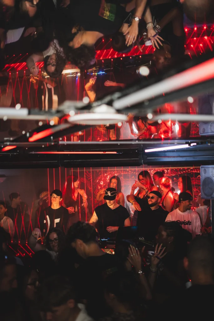 DJ en train de mixer devant une foule à La Dame Bordeaux avec ambiance rouge et lumières en club